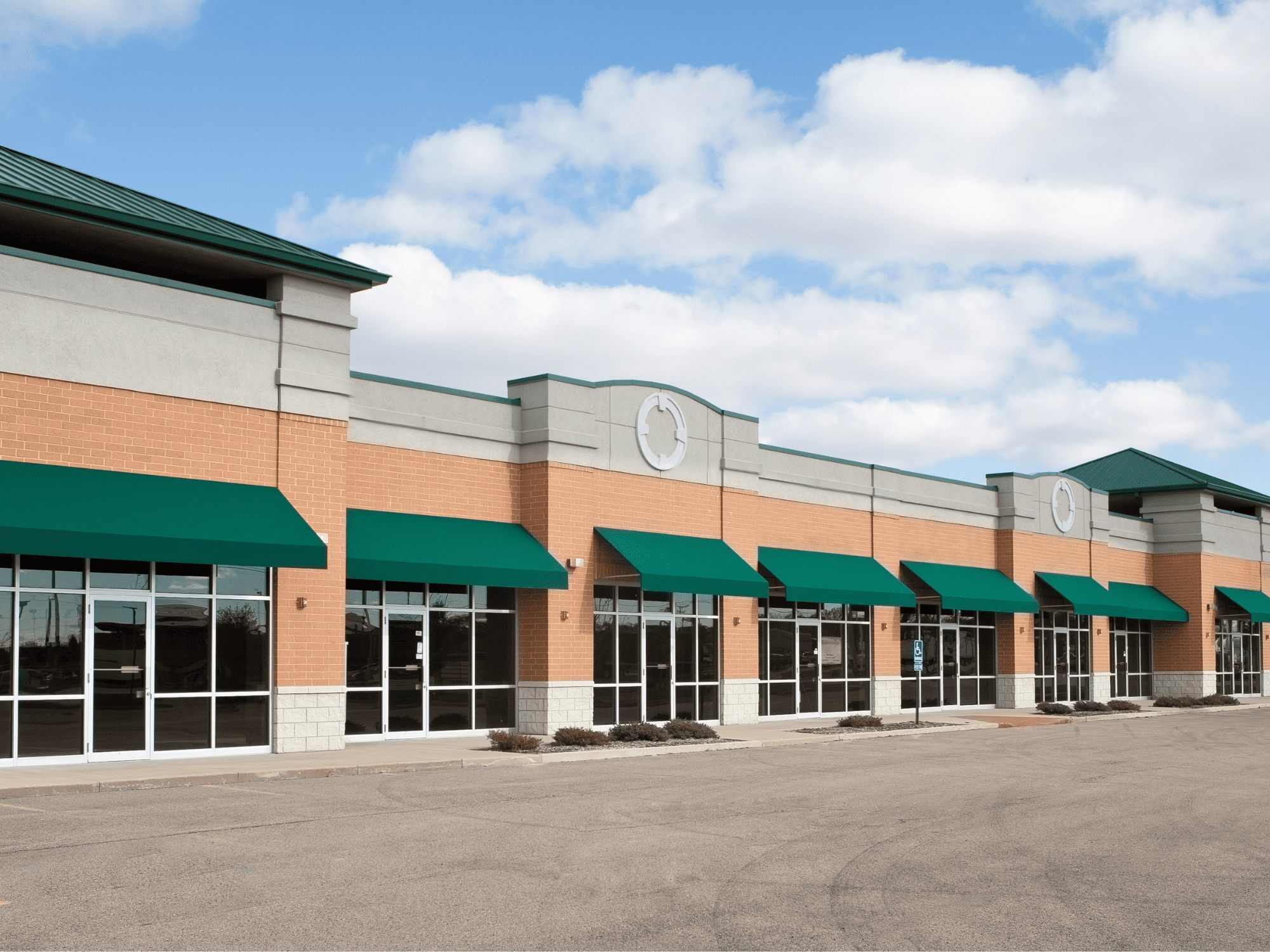 Strip mall storefront green awnings brick facade - stock